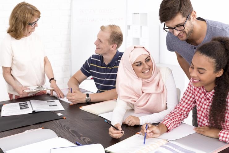 Praxissituation Soziale Arbeit, Arbeit, Integration, Soziale Sicherung Anleiterin erklärt einem Studierenden etwas und Studierende arbeiten gemeinsam an einer Aufgabe